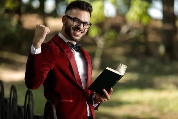 Affärsman håller bok och en näve upp full av glädje — Stockfoto