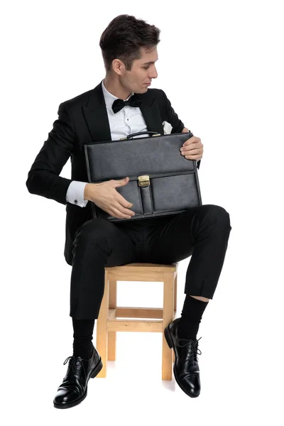 Jeune homme élégant en smoking tenant une valise — Photo