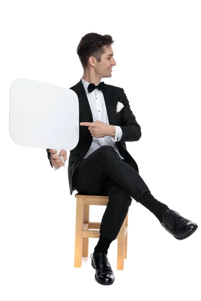 Happy young man presenting speech bubble to side — Stock Photo, Image