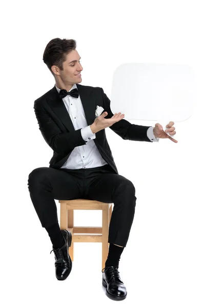 Usmívající se mladý muž držící a představující řečovou bublinu — Stock fotografie