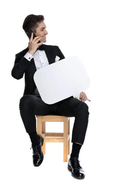 Happy young groom talking on the phone and holding speech bubble — Stock Photo, Image