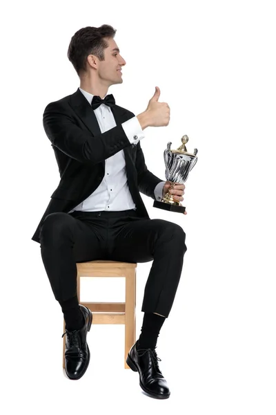 Proud young man making thumbs up sign and holding trophy — Stock Photo, Image