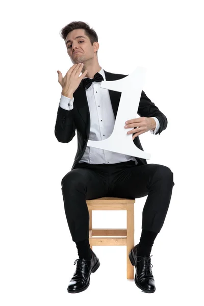 Ung elegant man med nummer ett tecken och rörande haka — Stockfoto