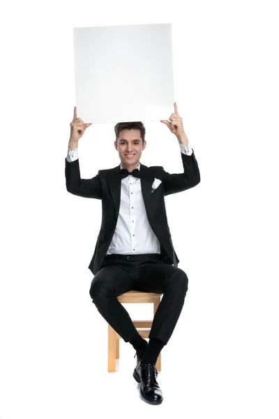 Happy young model holding empty board above head — 스톡 사진