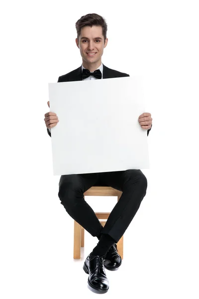 Szczęśliwy młody człowiek trzyma pustą deskę i uśmiecha się — Zdjęcie stockowe