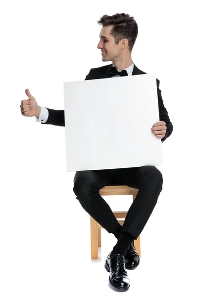 Happy young man holding empty board and making thumbs up sign — 스톡 사진