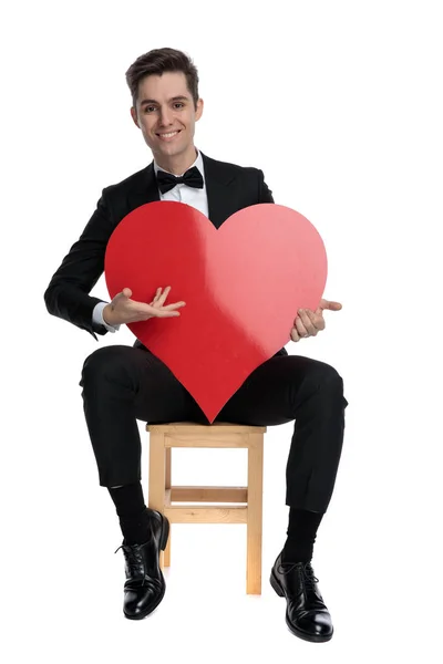 Happy young elegant man holding big red heart — Stock Photo, Image