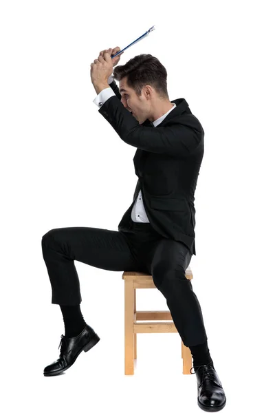 Young elegant man in tuxedo defending himself with clipboard — Stock Photo, Image