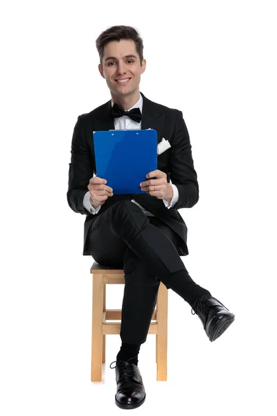 Feliz joven chico moderno sonriendo y sujetando portapapeles — Foto de Stock