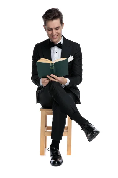 Feliz chico moderno en esmoquin lectura libro y sonriendo — Foto de Stock