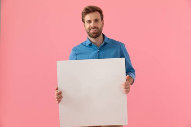 Kot gömlekli mutlu adam gülümsüyor ve tahtayı tutuyor.