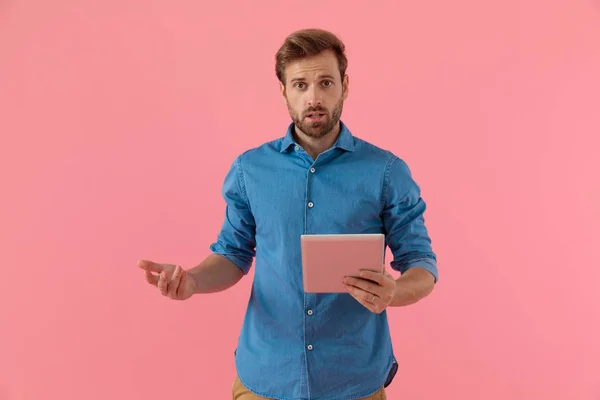 Shocked young guy in denim shirt on holding tab — 스톡 사진