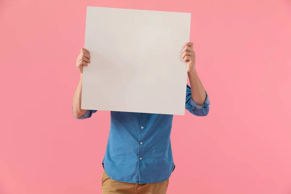 Casual guy covering face with empty board — Stock Photo, Image
