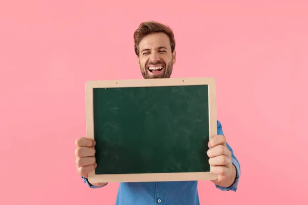 Leende avslappnad kille skrattar och håller svarta tavlan — Stockfoto