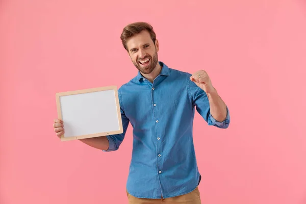 Happy casual guy holding empty board and celebrating victory — Stock Photo, Image