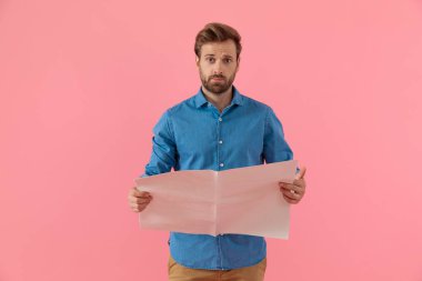 Gazete okuyan kafası karışmış genç bir adam.