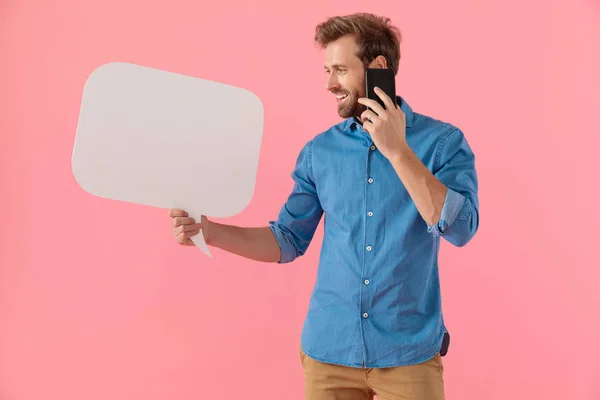 Happy casual guy holding speech bubble and talking on the phone — 스톡 사진