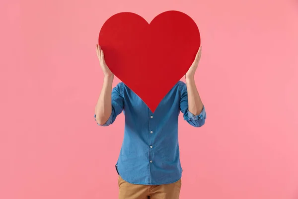 Casual chico en denim camisa cubriendo la cara con gran corazón rojo — Foto de Stock