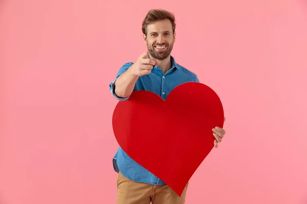 Glücklicher lässiger Typ, der lächelt und ein großes rotes Herz hält — Stockfoto