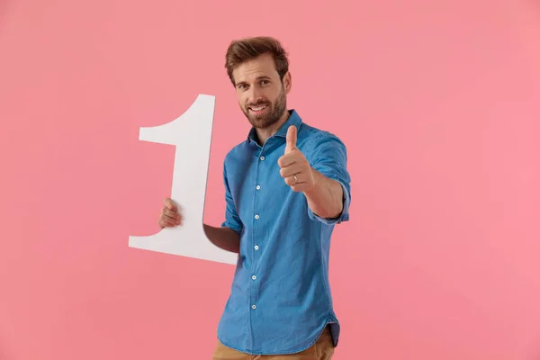 Glad kille håller nummer ett tecken och gör tummen upp tecken — Stockfoto