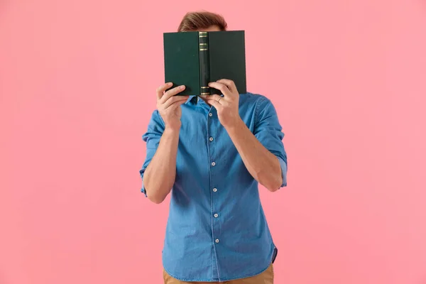 Casual guy in denim shirt verbergen achter boek — Stockfoto