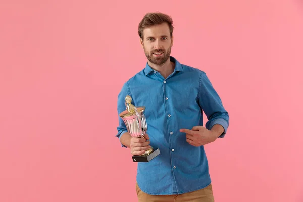 Cara casual feliz sorrindo e apontando dedo para troféu — Fotografia de Stock