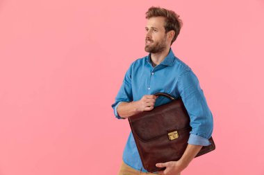 happy casual guy in denim shirt holding suitcase