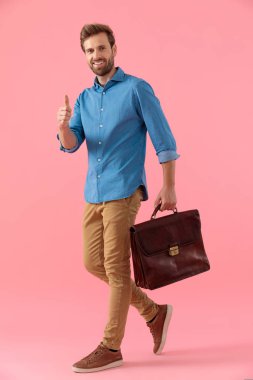 happy casual guy holding suitcase and making thumbs up sign
