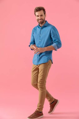 happy young guy in denim shirt laughing and rubbing palms