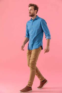 young casual man in denim shirt looking to side and walking
