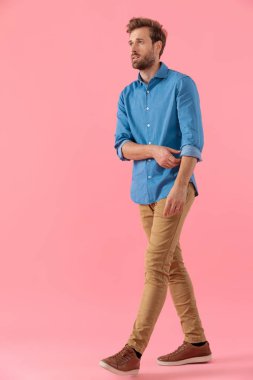 young casual guy in denim shirt looking to side and fixing sleev