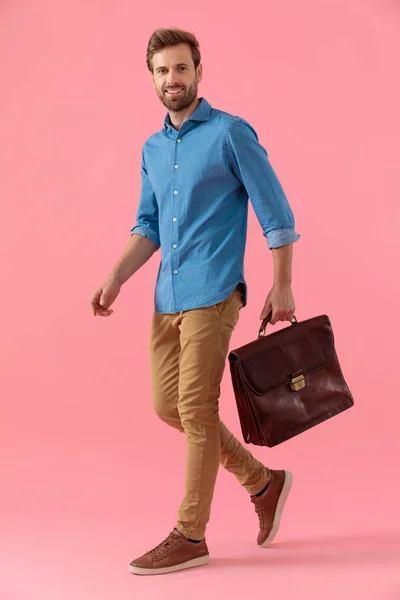 Gelukkig casual guy in denim shirt holding koffer en glimlachen — Stockfoto