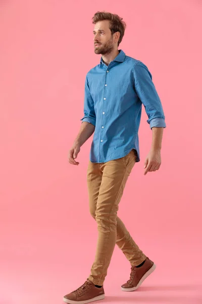 Młody dorywczy mężczyzna w dżinsowej koszuli patrząc w bok i spacerując — Zdjęcie stockowe
