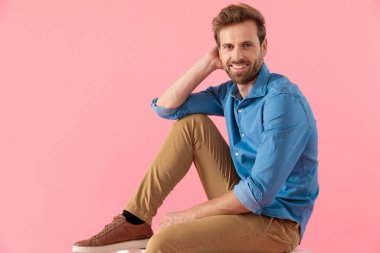 happy young casual man holding hand to head and smiling