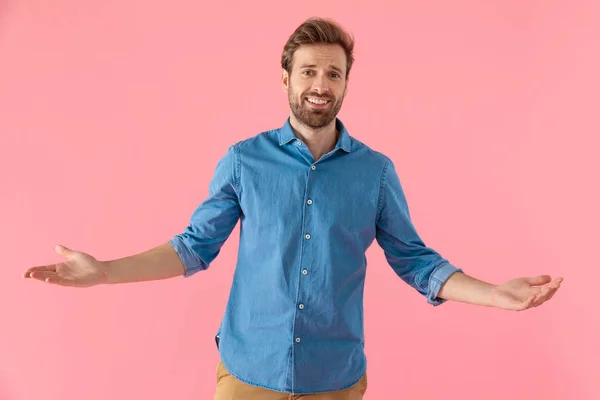 Joven feliz en camisa de mezclilla sonriendo y abriendo los brazos — Foto de Stock