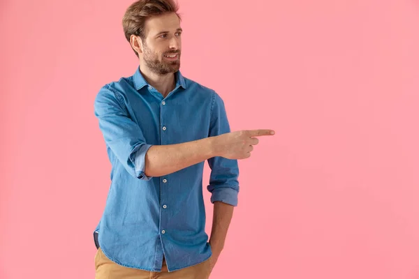 Modelo casual feliz en camisa de mezclilla sonriendo y señalando el dedo a — Foto de Stock