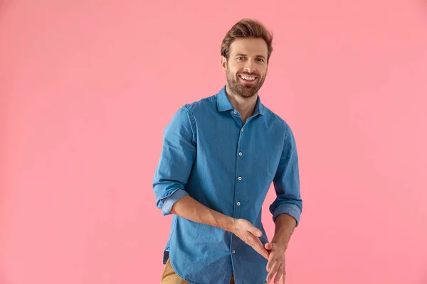 Hombre casual feliz en camisa de mezclilla sonriendo y frotando las palmas — Foto de Stock