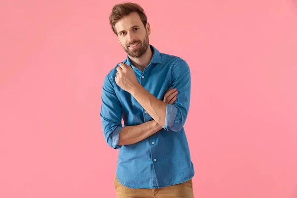 Hombre casual feliz sosteniendo el codo en pose de moda y sonriendo — Foto de Stock