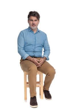 Sıkıntılı sıradan bir adam ileriye bakıyor ve ellerini bir arada tutuyor.
