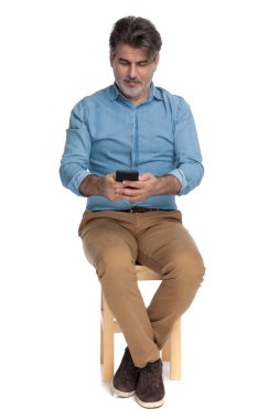 Telefonuna yazı yazan ve gülümseyen sıradan bir adam.