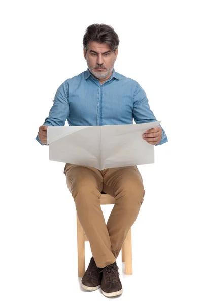 Besorgter Gelegenheitsmann liest Zeitung und runzelt die Stirn — Stockfoto
