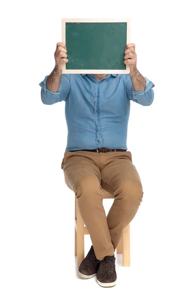 Old casual man covering his face with a blackboard — Stock Photo, Image