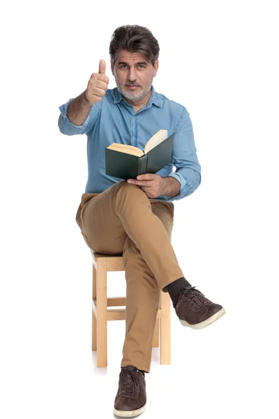 Positivo uomo casuale leggere un libro e dare pollici in su — Foto Stock