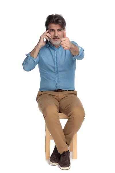 Pozytywny, swobodny mężczyzna rozmawiający przez telefon i podnoszący kciuki — Zdjęcie stockowe