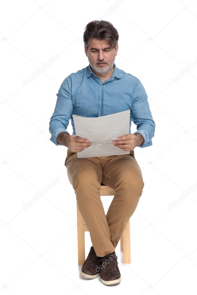 Bothered casual man reading a newspaper and frowning