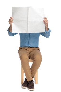 Yaşlı sıradan bir adam gazeteyle yüzünü örtüyor.