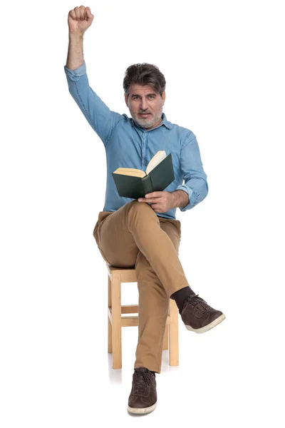 Alegre hombre casual leyendo un libro y celebrando —  Fotos de Stock