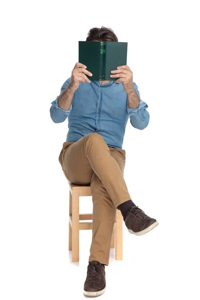 Alter, lässiger Mann, der sein Gesicht mit einem Buch bedeckt — Stockfoto
