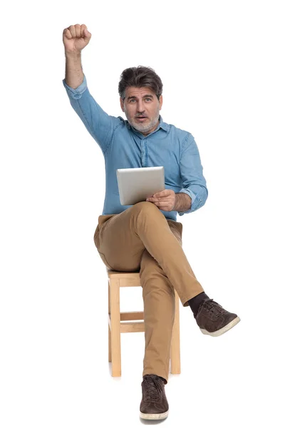 Cheerful casual man holding his tablet and celebrating — 스톡 사진