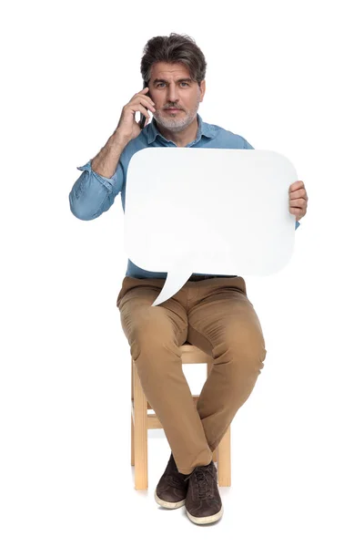 Впевнений випадковий чоловік розмовляє по телефону і тримає мовну бульбашку — стокове фото